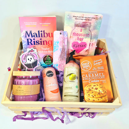 book gift box, reading subscription box containing paperbacks Malibu rising by Taylor Jenkins Reid and A Thousand Boy Kisses, candle, soda can, body lotion moisturiser, cookies, bookmark, stickers, bookish merch